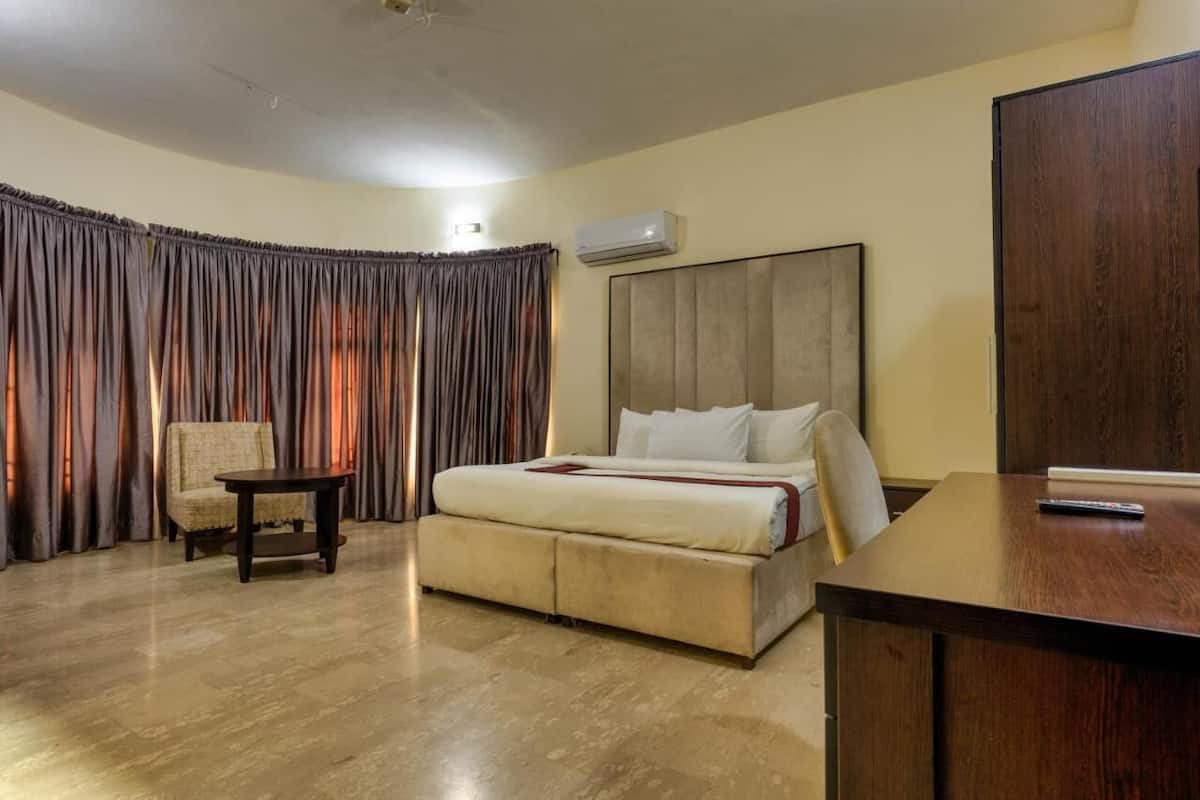 Una habitación de hotel con una cama grande, una mesita, una silla y un armario.