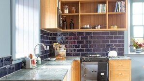 Una cuina amb armaris de fusta, forn integrat i finestra amb vistes.