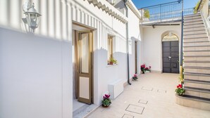 Un edificio blanco con una escalera, una puerta y plantas en macetas.