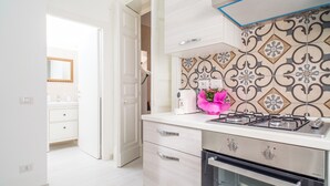 Una cocina moderna con estufa a gas, horno y muebles blancos.