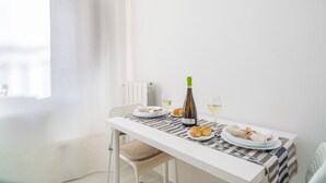 Una mesa de comedor con platos, una botella y vasos, frente a una pared blanca con una ventana.
