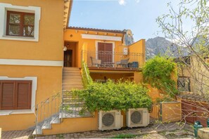 A yellow building with a balcony, air conditioning units, and a staircase.