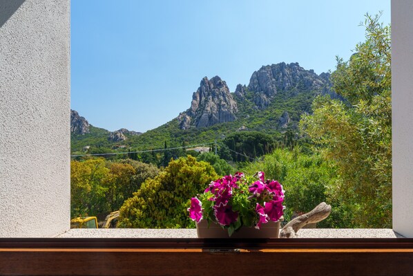 A window view of a mountainous landscape with a potted plant on the windowsill.