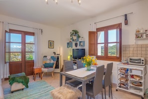 A compact living space with a dining area, kitchenette, and a TV.