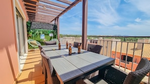 Un balcón con una mesa, sillas y botellas, con vista a la ciudad.