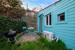 Uma casa azul com um pequeno alpendre, churrasqueira e ventoinha.