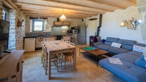 Hyggelig indretning med spisebord, sofa, køkken og stenvægge.