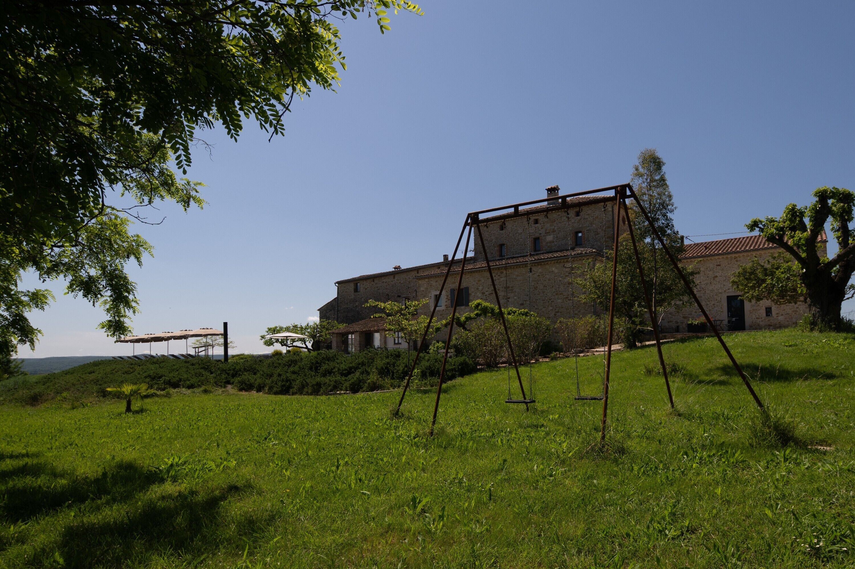 A large stone building with a swing set in a grassy field.