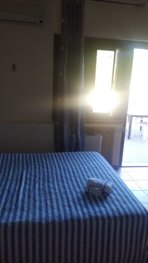 Ein Hotelzimmer mit Bett, Fenster mit Vorhängen und einer Klimaanlage.
