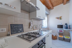 A modern kitchen with a gas stove, a sink, and a chalkboard with a message.