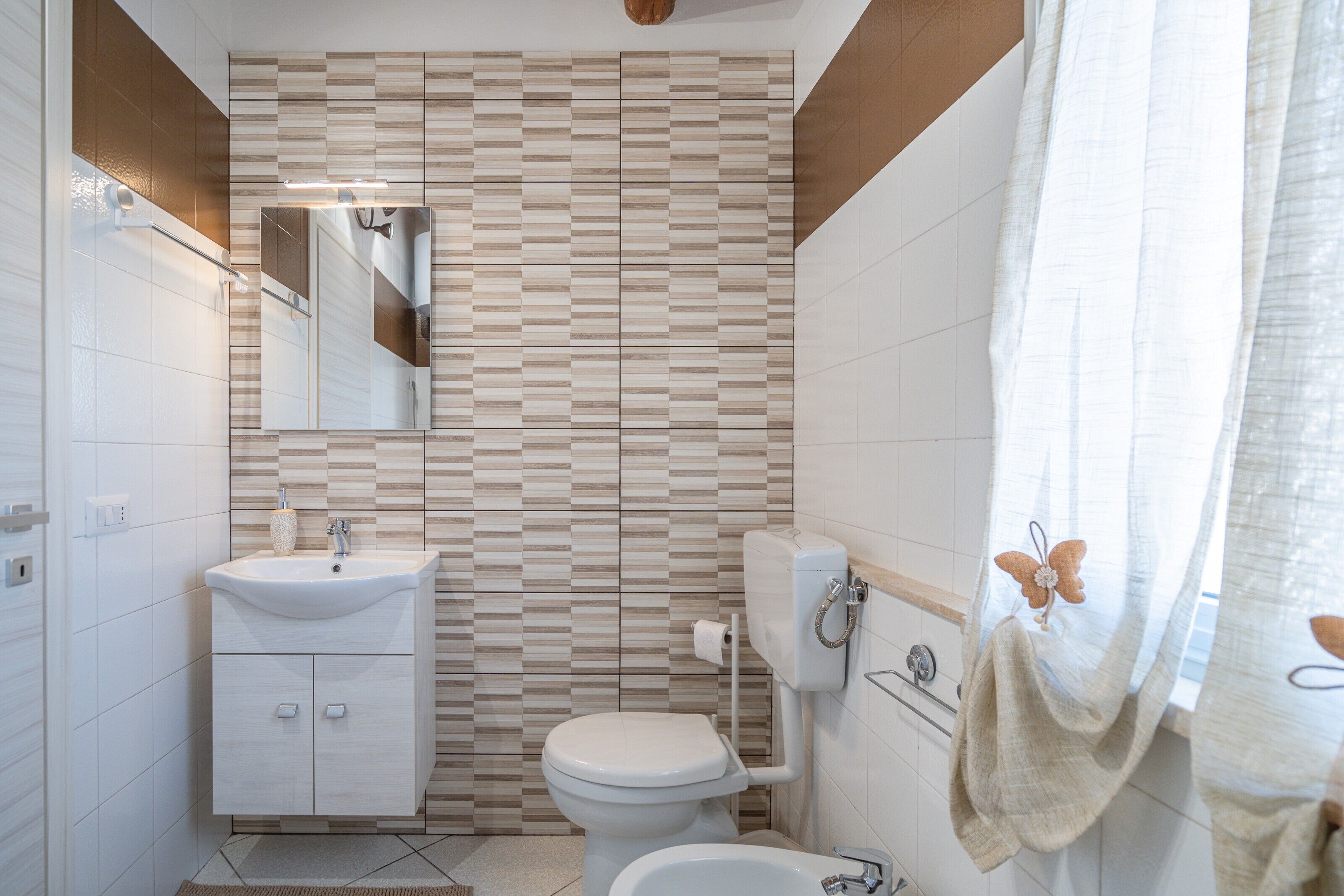 Une salle de bain avec un mur carrelé, un lavabo, des toilettes et un rideau de douche.
