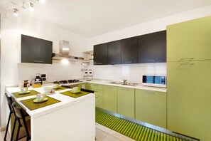 Une cuisine moderne dotée d’un îlot central, de plans de travail blancs et de meubles de couleur verte.