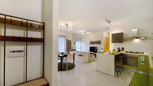 A modern kitchen with a central island, a dining area with a sofa, and a living room with a TV. - Apartment 'Appartamento Da Jenny' with Mountain View, Balcony and Wi-Fi (aosta)