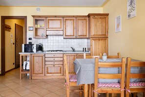Una cocina con armarios de madera, una mesa de comedor con sillas y una cafetera.