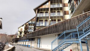 Ein mehrstöckiges Gebäude mit Balkonen, einer Garagentür und einer blauen Treppe.