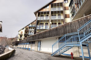 Un edificio de varios pisos con balcones, una puerta de garaje y una escalera azul.