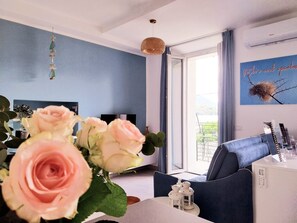 A modern living room with a blue wall, a large window, a sofa, a TV, and a decorative wall piece.