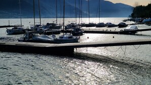 A marina with boats docked, a wooden pier, and mountains in the background. - Apartment 'Vichi's Nest' with Lake View, Wi-Fi and Air Conditioning (Pianello Del Lario)