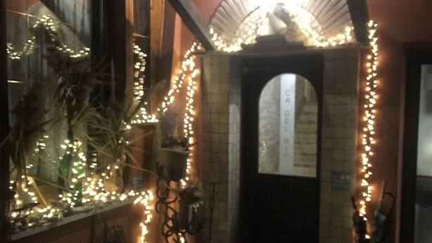 An interior corridor with a brick wall, a wooden bench, and string lights. - relais Cà del rio (Pianoro)