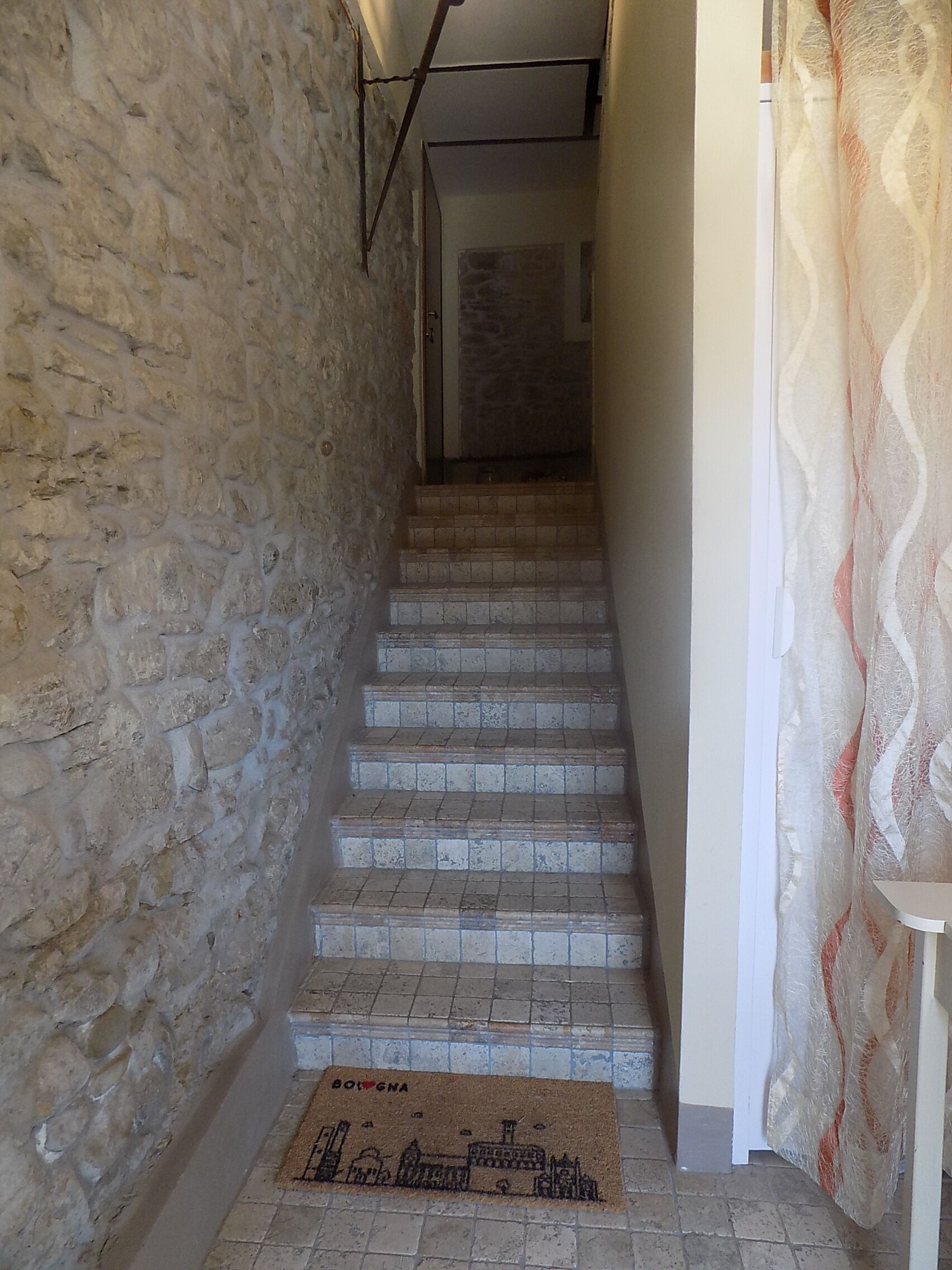 A staircase with stone walls and a doormat with a cityscape design.