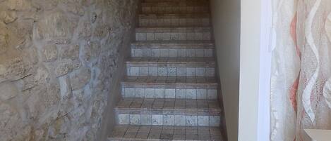 A staircase with stone walls and a doormat with a cityscape design.