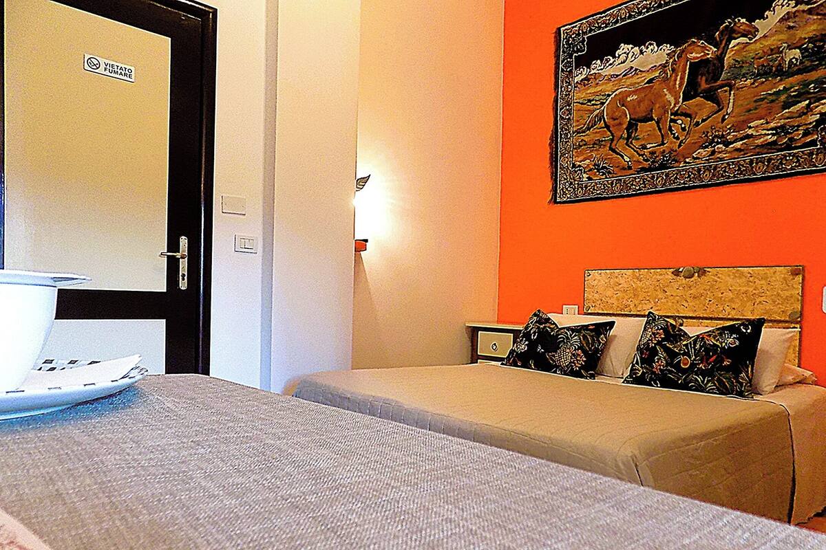 A hotel room with two beds, a door with a sign, a nightstand, and a wall painting.