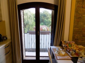 A room with a view of a balcony, a table with various items, and a door with a handle.