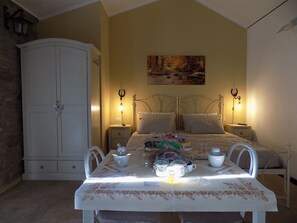 A bedroom with a bed, bedside tables, a wardrobe, and a dining table with chairs.