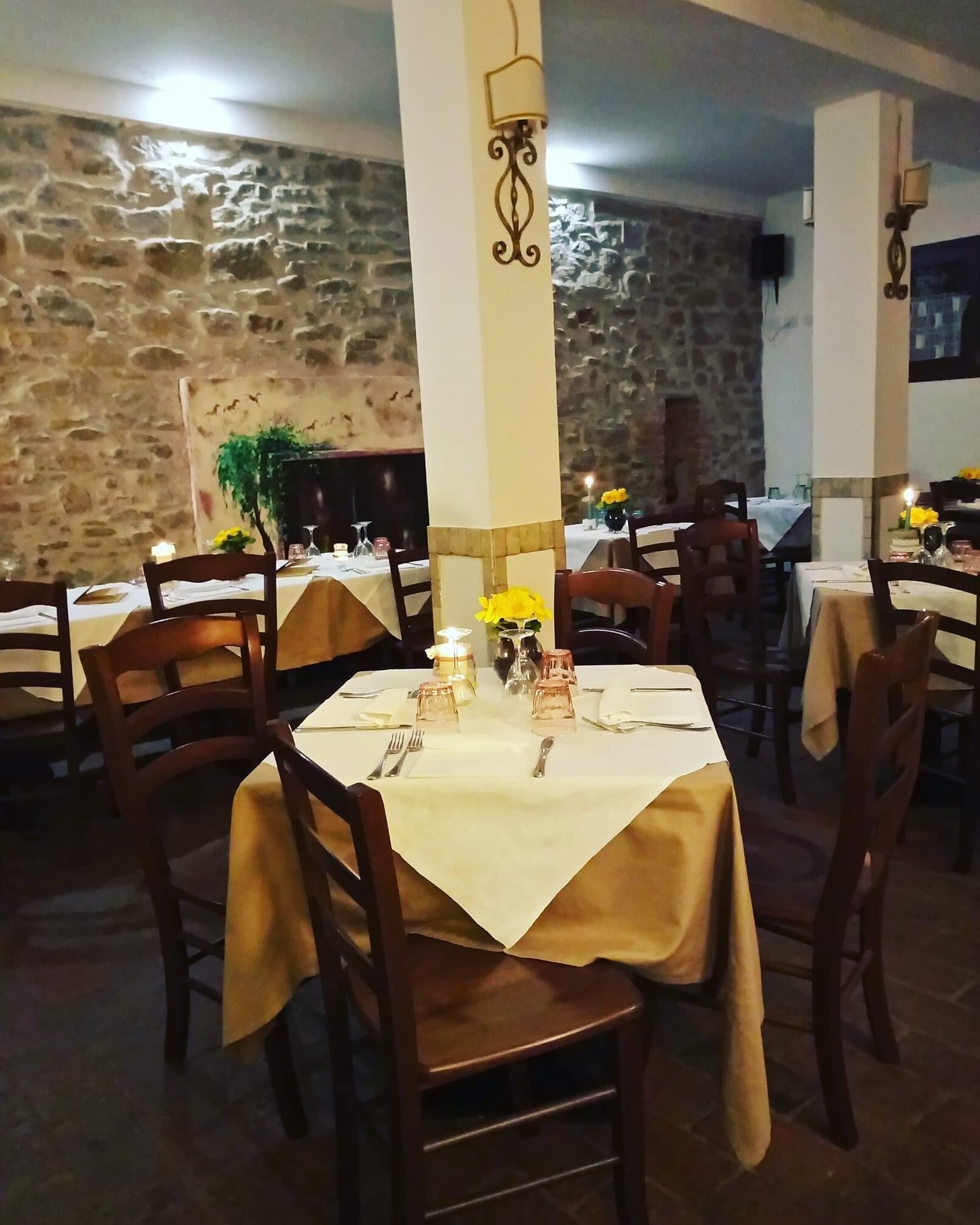 Een restaurant met stenen muren, houten tafels en stoelen.