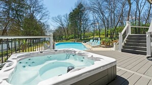 A hot tub on a wooden deck with a pool in the background, surrounded by trees. - Huge Lakehouse w/Pool, Hot Tub & Fire Pit Near Nashville! (Hendersonville)
