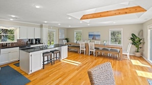 Una cocina amplia con una isla central, piso de madera y ventanas grandes.