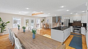 A spacious kitchen with white cabinets, a central island, and a dining area with a wooden table and chairs. - Huge Lakehouse w/Pool, Hot Tub & Fire Pit Near Nashville! (Hendersonville)