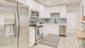 A modern kitchen with white cabinets, stainless steel appliances, a microwave, oven, and dishwasher. - Heated Pool + Backyard: North Palm Beach Retreat! (North Palm Beach)