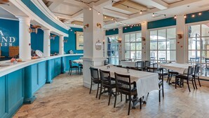 A restaurant interior with a curved counter, wooden chairs, and large windows. - North Topsail Beach Condo in Resort-Style Complex! (North Topsail Beach)