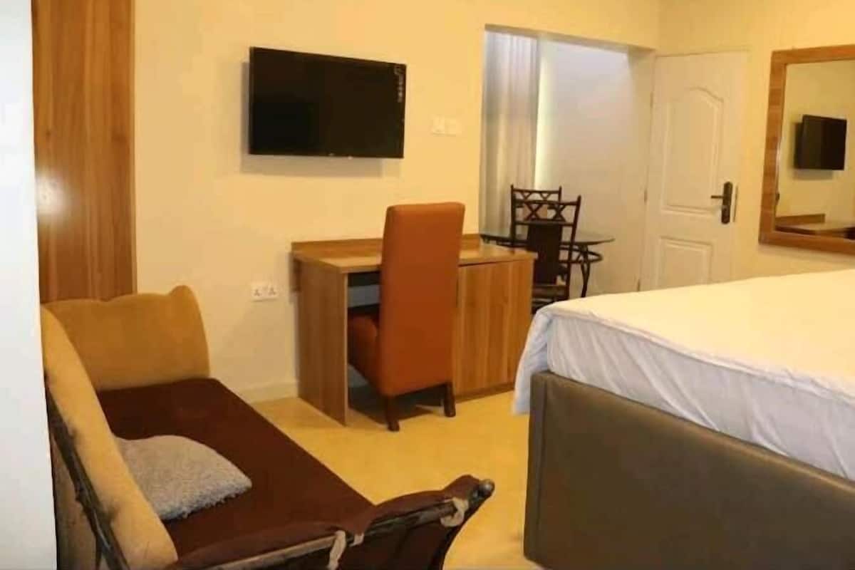 Ein Hotelzimmer mit Bett, Schreibtisch mit Stuhl, Fernseher und einer Tür.