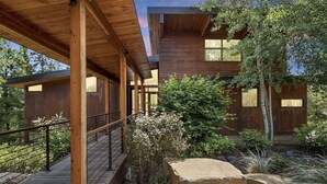 A modern wooden cabin with a covered porch, a stone pathway, and a garden with various plants and a large rock. - Rinky Dink Retreat - Suncadia LUXE With MIL Suite and Hot Tub (Cle Elum)