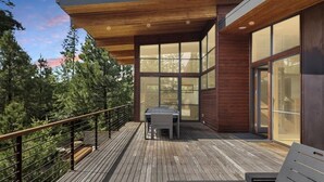 A modern outdoor deck with a wooden floor, a table, and a bench. - Rinky Dink Retreat - Suncadia LUXE With MIL Suite and Hot Tub (Cle Elum)