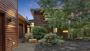 A modern wooden building with a covered entrance and a landscaped garden. - Rinky Dink Retreat - Suncadia LUXE With MIL Suite and Hot Tub (Cle Elum)