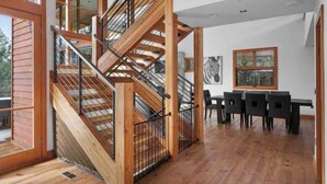 A modern interior with a wooden staircase, a dining area with black chairs, and a zebra artwork on the wall. - Rinky Dink Retreat - Suncadia LUXE With MIL Suite and Hot Tub (Cle Elum)
