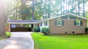 A single-story brick house with a covered porch, a lawn, and a driveway. - Peace in the City (Decatur)