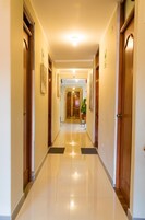 Pasillo de hotel con puertas de madera, piso de baldosas y una lámpara en el techo.