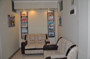 Un vestíbulo con dos sofás, un televisor de pared y cuadros enmarcados de diferentes destinos.