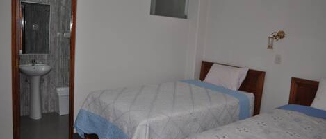 Un dormitorio con dos camas, una ventana, un lavamanos y un espejo.