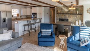 A spacious living area with a fireplace, a kitchen with white cabinets, and a dining area with a stone accent wall. - Screne Cabin, Dock, Beach, HotTub, FirePit, Kayak (Goodview)