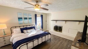 A bedroom with a bed, a ceiling fan, a fireplace, and a TV. - Screne Cabin, Dock, Beach, HotTub, FirePit, Kayak (Goodview)