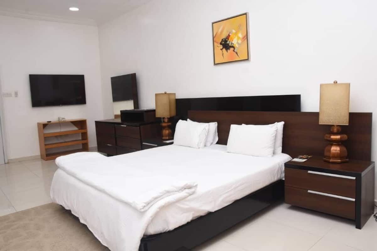 Una habitación de hotel moderna con una cama grande, un televisor, un escritorio y una lámpara.