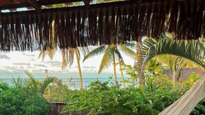 A hammock with a white netted bottom, a blue pool, and a view of palm trees and the ocean. - Pousada Nascente do Sol (Cairu)