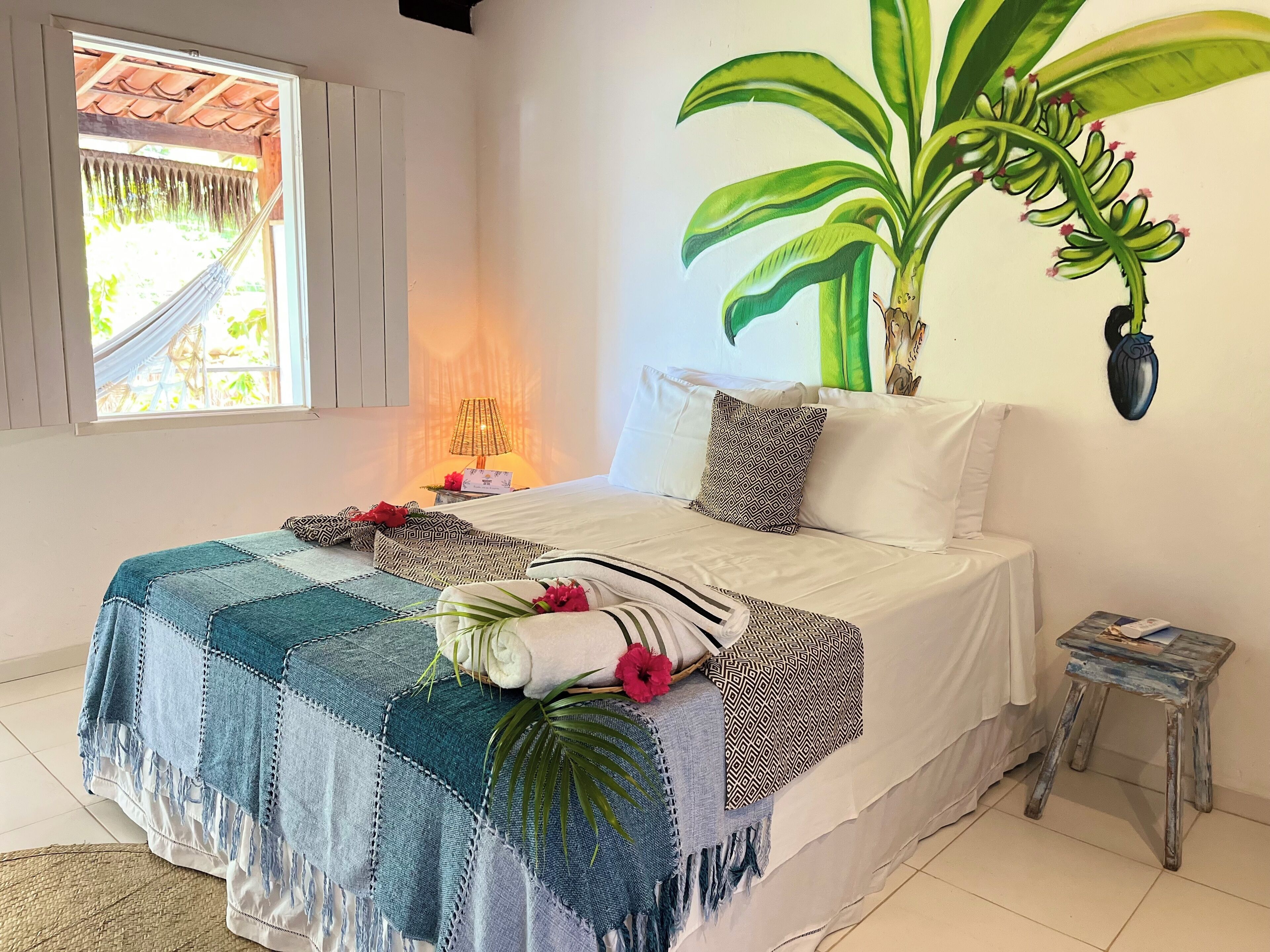A bedroom with a bed, a hammock, a lamp, and a wall-mounted plant.