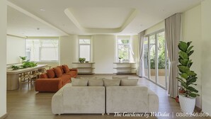 A spacious living room with a large sofa, a smaller sofa, and a dining area with a table and chairs. There are multiple windows providing natural light and views of the outdoors. - The Gardener by WeDalat (Xuan Huong - Da Lat)