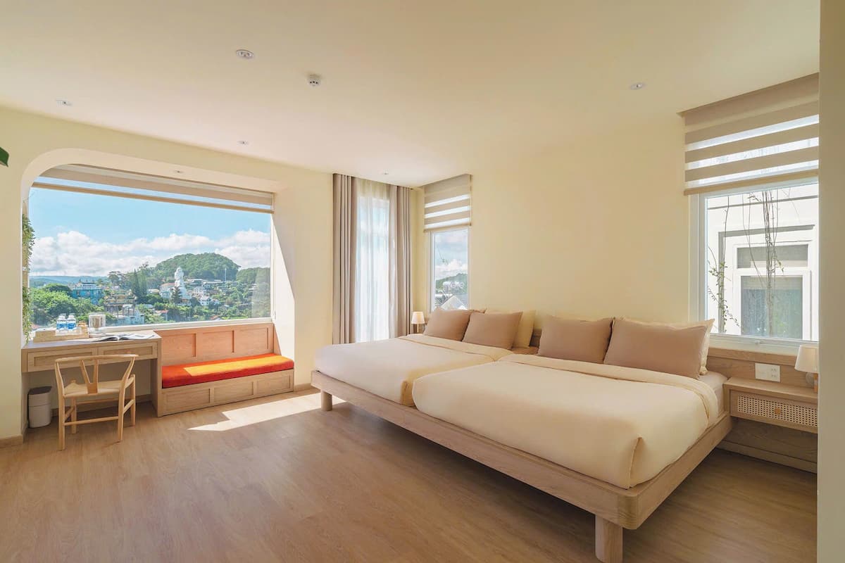 A spacious bedroom with a large bed, a desk, and a view of a cityscape.
